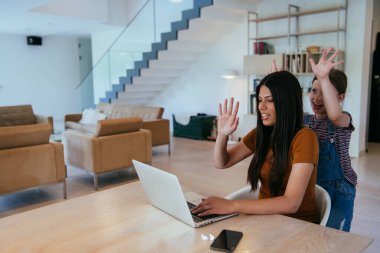 Anne ve kızı dizüstü bilgisayarda ailesi ve arkadaşlarıyla konuşuyorlardı. Büyük evin modern oturma odasında oturuyorlardı.