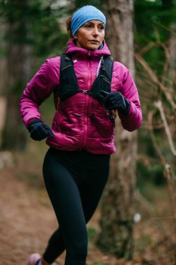 Yoğun Çam Ormanı 'nda Odaklanarak Koşan Kararlı Kadın Atletizm Gücü ve Doğayı Kucaklayan.