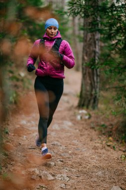 Yoğun Çam Ormanı 'nda Odaklanarak Koşan Kararlı Kadın Atletizm Gücü ve Doğayı Kucaklayan.