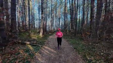 Dağlardaki bir sonbahar ormanında koşan dişi bir koşucunun gizli bir fotoğrafı. Sabah sporları aktif yaşam tarzı, uygunluk, dayanıklılık ve doğa odaklı eğitim maratonunu gözler önüne seriyor