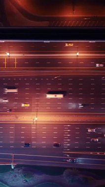 Parlayan gece trafiğinin, akıllı Dubai şehrindeki fütüristik gökdelenlerle çevrili otoyol kavşaklarından dokumasının en üst görüntüsü. Canlı şehir ışıkları, modern ufuk çizgisi ve şehir mimarisi.