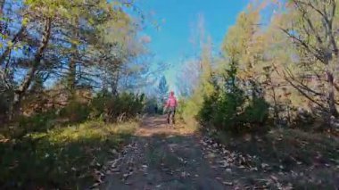 Dağlardaki bir sonbahar ormanında koşan dişi bir koşucunun gizli bir fotoğrafı. Sabah sporları aktif yaşam tarzı, uygunluk, dayanıklılık ve doğa odaklı eğitim maratonunu gözler önüne seriyor