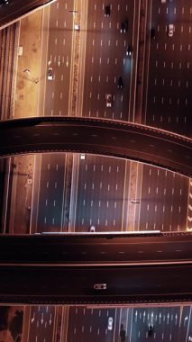 Parlayan gece trafiğinin, akıllı Dubai şehrindeki fütüristik gökdelenlerle çevrili otoyol kavşaklarından dokumasının en üst görüntüsü. Canlı şehir ışıkları, modern ufuk çizgisi ve şehir mimarisi.