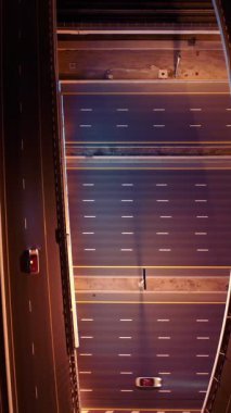 Parlayan gece trafiğinin, akıllı Dubai şehrindeki fütüristik gökdelenlerle çevrili otoyol kavşaklarından dokumasının en üst görüntüsü. Canlı şehir ışıkları, modern ufuk çizgisi ve şehir mimarisi.