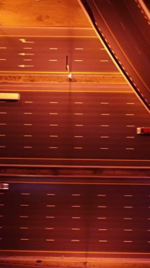 Parlayan gece trafiğinin, akıllı Dubai şehrindeki fütüristik gökdelenlerle çevrili otoyol kavşaklarından dokumasının en üst görüntüsü. Canlı şehir ışıkları, modern ufuk çizgisi ve şehir mimarisi.