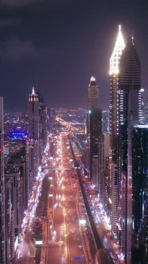 İkonik gökdelenlerin gece görüşü ve Dubai, BAE 'deki büyük bir kavşakta yoğun trafik. Modern bir şehrin çarpıcı silueti iş, finans ve kentsel gelişimi sembolize ediyor..