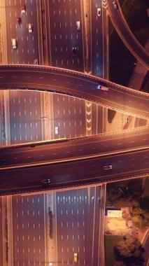 Parlayan gece trafiğinin, akıllı Dubai şehrindeki fütüristik gökdelenlerle çevrili otoyol kavşaklarından dokumasının en üst görüntüsü. Canlı şehir ışıkları, modern ufuk çizgisi ve şehir mimarisi.
