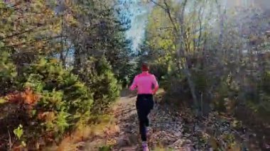 Dağlardaki bir sonbahar ormanında koşan dişi bir koşucunun gizli bir fotoğrafı. Sabah sporları aktif yaşam tarzı, uygunluk, dayanıklılık ve doğa odaklı eğitim maratonunu gözler önüne seriyor