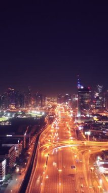 İkonik gökdelenlerin gece görüşü ve Dubai, BAE 'deki büyük bir kavşakta yoğun trafik. Modern bir şehrin çarpıcı silueti iş, finans ve kentsel gelişimi sembolize ediyor..