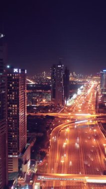 İkonik gökdelenlerin gece görüşü ve Dubai, BAE 'deki büyük bir kavşakta yoğun trafik. Modern bir şehrin çarpıcı silueti iş, finans ve kentsel gelişimi sembolize ediyor..