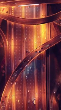 Parlayan gece trafiğinin, akıllı Dubai şehrindeki fütüristik gökdelenlerle çevrili otoyol kavşaklarından dokumasının en üst görüntüsü. Canlı şehir ışıkları, modern ufuk çizgisi ve şehir mimarisi.