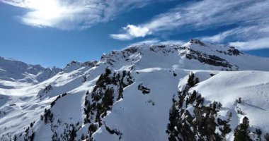 Karla kaplı dağların, güneşli gökyüzünün ve kayak, snowboard, yürüyüş ve açık hava maceraları için mükemmel manzaralı yamaçların nefes kesici hava manzarası.