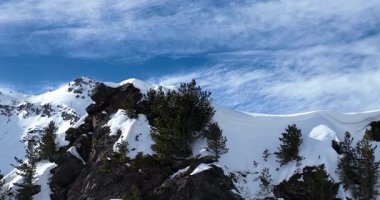 Karla kaplı dağların, güneşli gökyüzünün ve kayak, snowboard, yürüyüş ve açık hava maceraları için mükemmel manzaralı yamaçların nefes kesici hava manzarası.