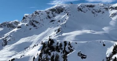 Karla kaplı dağların, güneşli gökyüzünün ve kayak, snowboard, yürüyüş ve açık hava maceraları için mükemmel manzaralı yamaçların nefes kesici hava manzarası.