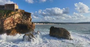 Güneş batarken kayalık bir kıyıya çarpan derin mavi okyanus dalgalarının dramatik hava manzarası bu sakin tropikal deniz manzarasını güzelleştirir. Seyahat, tatil ve doğa temaları için mükemmeldir..