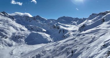 Karla kaplı dağların, güneşli gökyüzünün ve kayak, snowboard, yürüyüş ve açık hava maceraları için mükemmel manzaralı yamaçların nefes kesici hava manzarası.