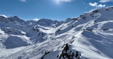 Karla kaplı dağların, güneşli gökyüzünün ve kayak, snowboard, yürüyüş ve açık hava maceraları için mükemmel manzaralı yamaçların nefes kesici hava manzarası.