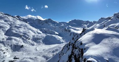 Karla kaplı dağların, güneşli gökyüzünün ve kayak, snowboard, yürüyüş ve açık hava maceraları için mükemmel manzaralı yamaçların nefes kesici hava manzarası.