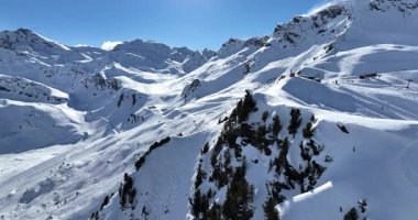 Karla kaplı dağların, güneşli gökyüzünün ve kayak, snowboard, yürüyüş ve açık hava maceraları için mükemmel manzaralı yamaçların nefes kesici hava manzarası.