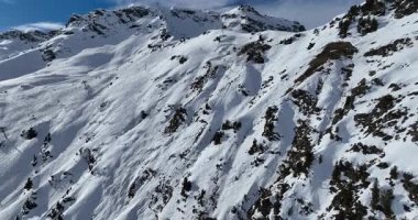 Karla kaplı dağların, güneşli gökyüzünün ve kayak, snowboard, yürüyüş ve açık hava maceraları için mükemmel manzaralı yamaçların nefes kesici hava manzarası.