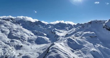 Karla kaplı dağların, güneşli gökyüzünün ve kayak, snowboard, yürüyüş ve açık hava maceraları için mükemmel manzaralı yamaçların nefes kesici hava manzarası.
