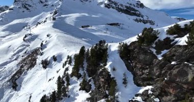 Karla kaplı dağların, güneşli gökyüzünün ve kayak, snowboard, yürüyüş ve açık hava maceraları için mükemmel manzaralı yamaçların nefes kesici hava manzarası.