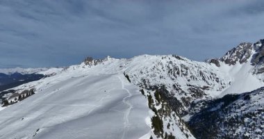 Karla kaplı dağların, güneşli gökyüzünün ve kayak, snowboard, yürüyüş ve açık hava maceraları için mükemmel manzaralı yamaçların nefes kesici hava manzarası.