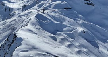 Karla kaplı dağların, güneşli gökyüzünün ve kayak, snowboard, yürüyüş ve açık hava maceraları için mükemmel manzaralı yamaçların nefes kesici hava manzarası.