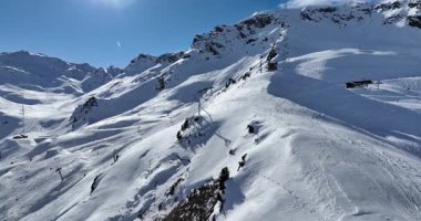 Karla kaplı dağların, güneşli gökyüzünün ve kayak, snowboard, yürüyüş ve açık hava maceraları için mükemmel manzaralı yamaçların nefes kesici hava manzarası.