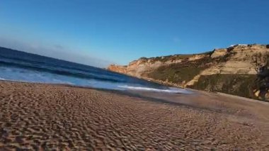 FPV insansız hava aracı, Portekiz 'in Nazare Sahili' ndeki kayalık kıyılara çarpan güçlü dalgaları gösteriyor. Uçurumlar, turkuvaz okyanuslar ve manzaralı yaz atmosferiyle çarpıcı bir sahil manzarası mükemmel bir kaçış yolu..