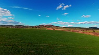 Dikey video FPV dron görüntüsü canlı yeşil alanlar üzerinde bankacılık ve dağınık bulutlar altında açık mavi gökyüzü altında yuvarlanan kırsal. Manzaralı kırsal alan, hızlı hareket, dinamik hava fpv dronu