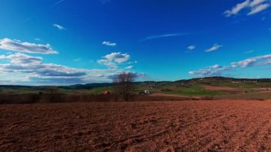 FPV 'nin insansız hava aracı görüntüsü canlı yeşil tarlaların ve açık mavi gökyüzünün altında dağınık bulutların üzerinde dönüyor. Manzaralı kırsal alan, hızlı hareket, dinamik hava fpv insansız hava aracı görüntüleri.