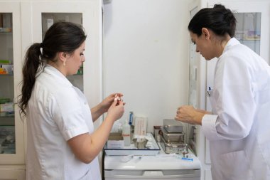 Bir hastane laboratuvarında iki hemşire hastalar ve hastane kullanımı için ilaçları dikkatlice inceliyor ve hazırlıyorlar.