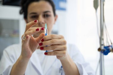 Beyaz önlüklü, odaklanmış bir hemşire profesyonel bir sağlık ortamında enjeksiyon için dikkatlice bir şırınga hazırlar.