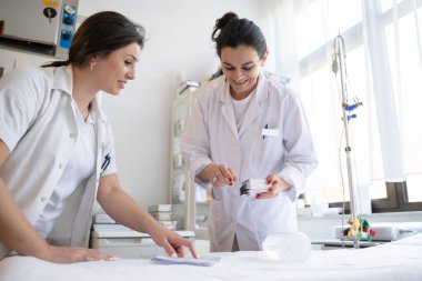 Bir hastane laboratuvarında iki hemşire hastalar ve hastane kullanımı için ilaçları dikkatlice inceliyor ve hazırlıyorlar.