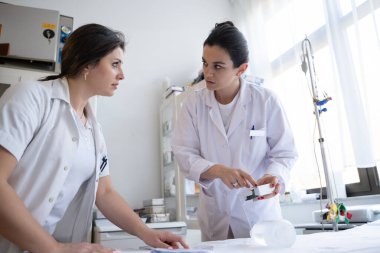 Bir hastane laboratuvarında iki hemşire hastalar ve hastane kullanımı için ilaçları dikkatlice inceliyor ve hazırlıyorlar.