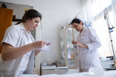 Bir hastane laboratuvarında iki hemşire hastalar ve hastane kullanımı için ilaçları dikkatlice inceliyor ve hazırlıyorlar.