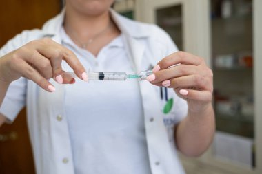 Beyaz önlüklü, odaklanmış bir hemşire profesyonel bir sağlık ortamında enjeksiyon için dikkatlice bir şırınga hazırlar.