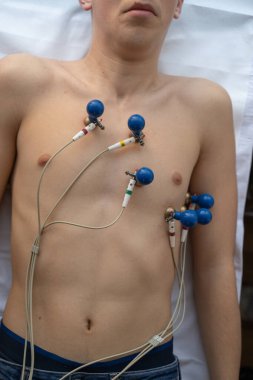 Kadın bir doktor, hastane odasında genç bir adama EKG çeker. Rutin bir kontrol sırasında kalp sağlığını dikkatle izler.
