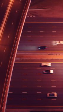 Parlayan gece trafiğinin, akıllı Dubai şehrindeki fütüristik gökdelenlerle çevrili otoyol kavşaklarından dokumasının en üst görüntüsü. Canlı şehir ışıkları, modern ufuk çizgisi ve şehir mimarisi.