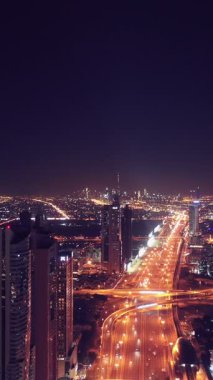 İkonik gökdelenlerin gece görüşü ve Dubai, BAE 'deki büyük bir kavşakta yoğun trafik. Modern bir şehrin çarpıcı silueti iş, finans ve kentsel gelişimi sembolize ediyor..