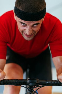 Modern bir oturma odasında triatlon bisikleti süren bir triatloncu. Pandemik koşullarda eğitim