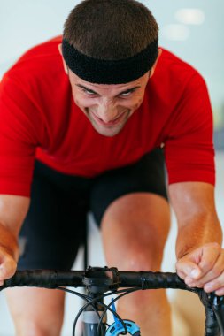 Modern bir oturma odasında triatlon bisikleti süren bir triatloncu. Pandemik koşullarda eğitim