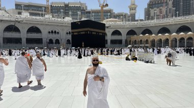 Kel bir adam, Mekke 'deki Mescid-i Haram' da Umrah 'ı sahneledikten sonra öğlen Kabe' nin önünde fotoğraf için poz veriyor. Kutsal Mescid-i Haram 'ın göbeğinde, parlak güneş ışığı altında kutsal bir hac..