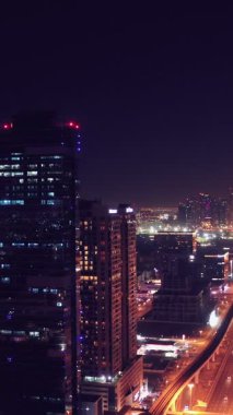 İkonik gökdelenlerin gece görüşü ve Dubai, BAE 'deki büyük bir kavşakta yoğun trafik. Modern bir şehrin çarpıcı silueti iş, finans ve kentsel gelişimi sembolize ediyor..