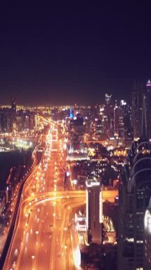 İkonik gökdelenlerin gece görüşü ve Dubai, BAE 'deki büyük bir kavşakta yoğun trafik. Modern bir şehrin çarpıcı silueti iş, finans ve kentsel gelişimi sembolize ediyor..