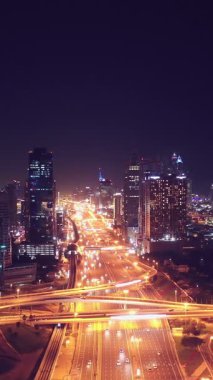 İkonik gökdelenlerin gece görüşü ve Dubai, BAE 'deki büyük bir kavşakta yoğun trafik. Modern bir şehrin çarpıcı silueti iş, finans ve kentsel gelişimi sembolize ediyor..
