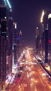 İkonik gökdelenlerin gece görüşü ve Dubai, BAE 'deki büyük bir kavşakta yoğun trafik. Modern bir şehrin çarpıcı silueti iş, finans ve kentsel gelişimi sembolize ediyor..