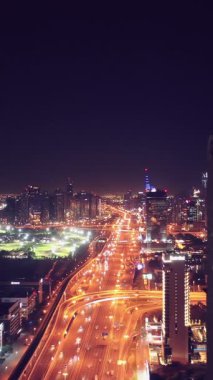 İkonik gökdelenlerin gece görüşü ve Dubai, BAE 'deki büyük bir kavşakta yoğun trafik. Modern bir şehrin çarpıcı silueti iş, finans ve kentsel gelişimi sembolize ediyor..