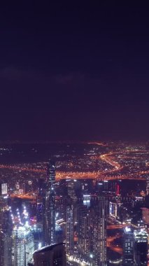 İkonik gökdelenlerin gece görüşü ve Dubai, BAE 'deki büyük bir kavşakta yoğun trafik. Modern bir şehrin çarpıcı silueti iş, finans ve kentsel gelişimi sembolize ediyor..